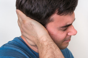 Man with earache is holding his aching ear - body pain concept
